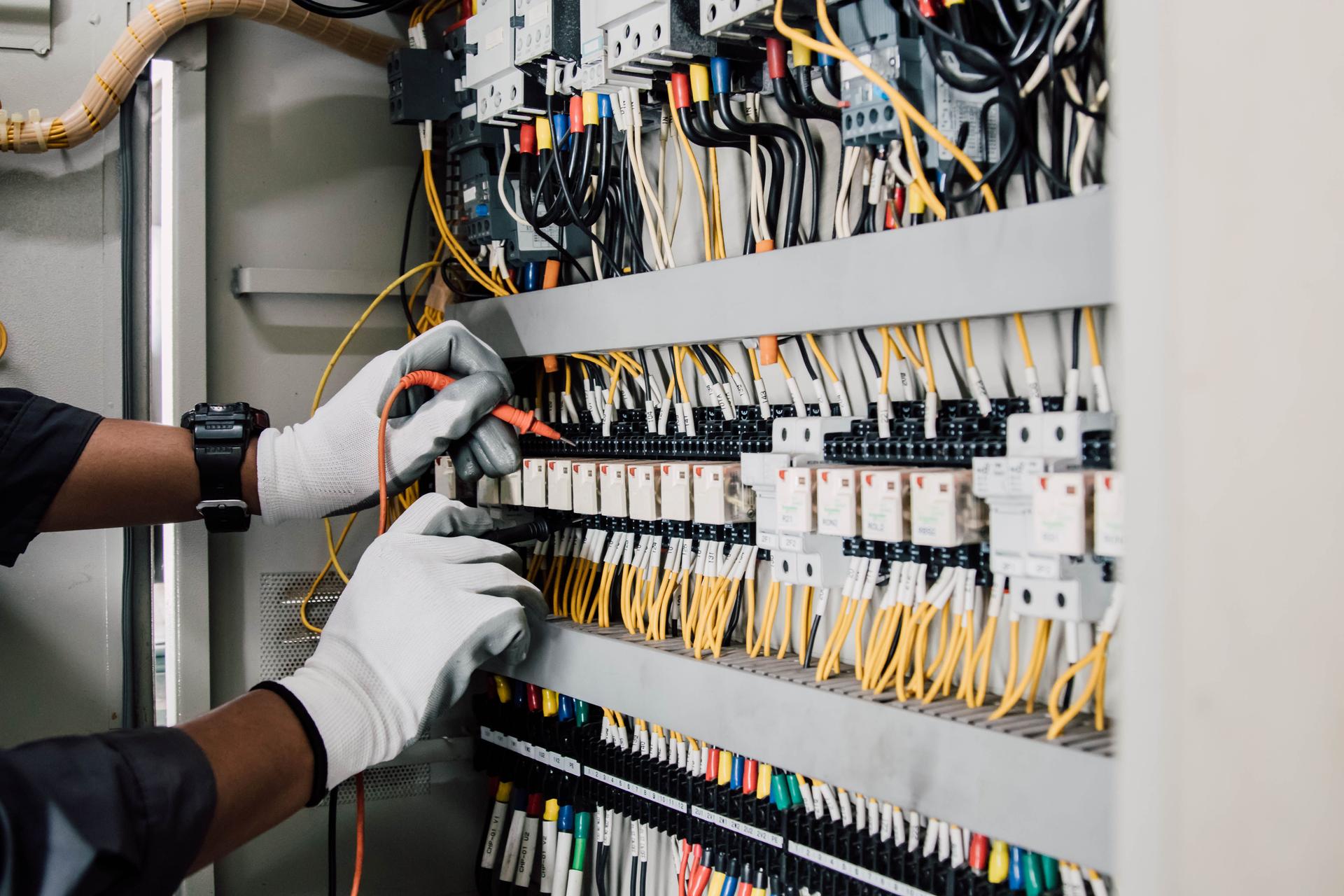 Electrician engineer tests electrical installations and wires on relay protection system.